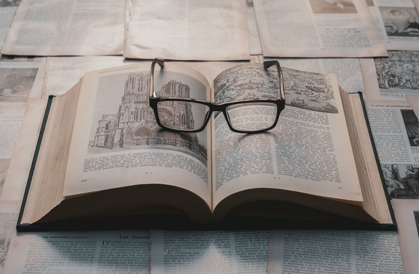 Libro antico con occhiali e pagine di mappe storiche.