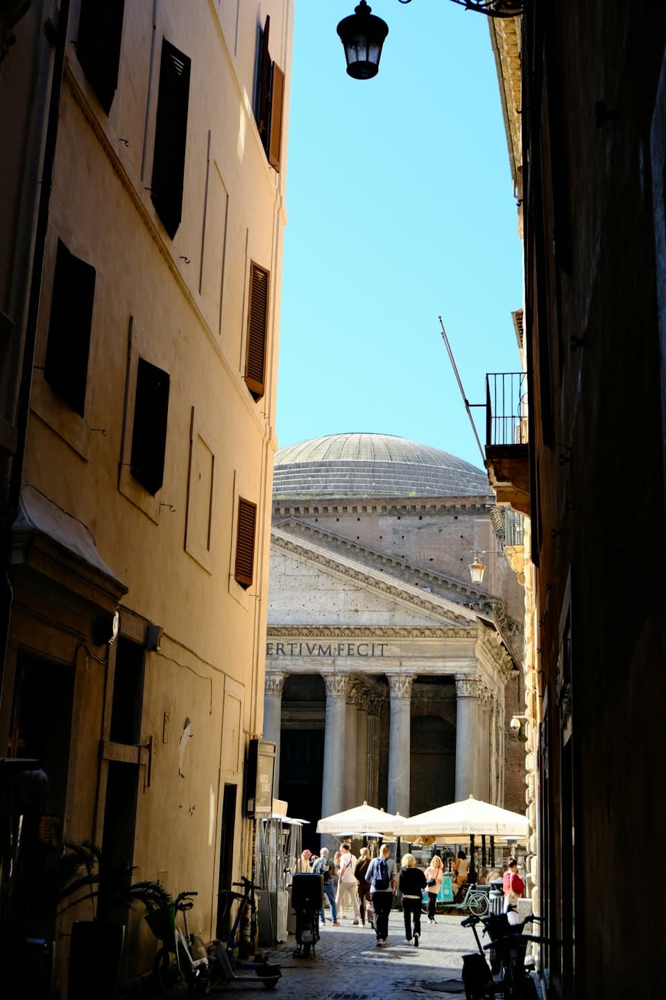 Persone camminano lungo una strada acciottolata verso un antico tempio.