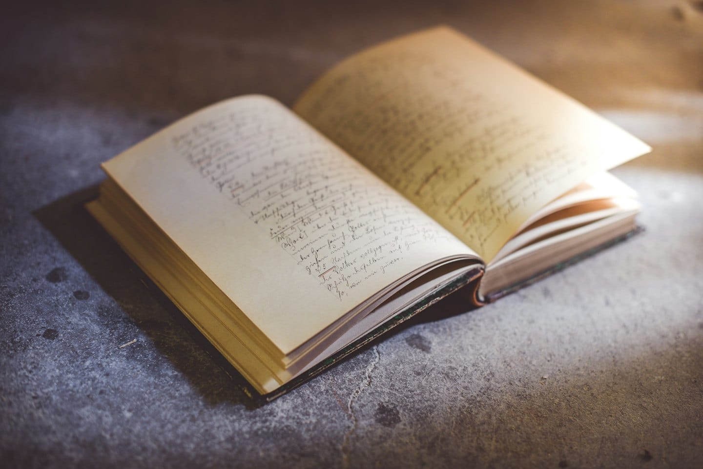 Un libro antico con scrittura a mano poggia su una superficie di pietra.